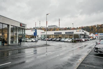 Vue d'ensemble d'un quartier de concessionnaires automobiles en Moselle, avec showrooms vitrés et véhicules exposés sur les parvis