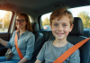Jeune adolescent souriant au volant d'une voiture moderne avec parent