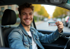 Assurance auto : assurance moins chère pour jeune permis ? Jeune homme souriant avec permis de conduire dans une voiture
