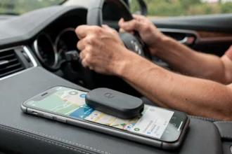 Traceur GPS sans abonnement posé sur le tableau de bord d'une voiture avec une application Android de navigation affichée sur un smartphone